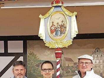 Diakon Joachim Stapf und Thomas Kirchner nehmen das sanierte Wallfahrtsbild aus der Hand von Malermeister Dieter Gerstenkorn aus Ebern (von links) in Empfang. Das Wallfahrtsbild zeigt auf einer Seite die "Krönung Mariens".  Foto: Johanna Muckelbauer