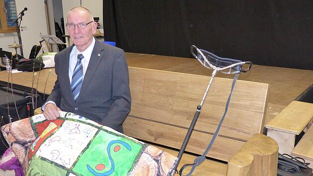 Das Lehrerkollegium &uuml;berraschte den zuk&uuml;nftigen Pensionisten mit einer wuchtigen Eichen-Sitzbank, die Werklehrer Brux angefertigt und in deren Lehne er das von Paul selbst entworfene Schullogo geschnitzt hat. Die Sch&uuml;ler bedankten sich bei ihrem "Chef" mit einer im Unterricht gestalteten Decke mit dem Schullogo sowie J&auml;germotiven Foto: Elmar Heill