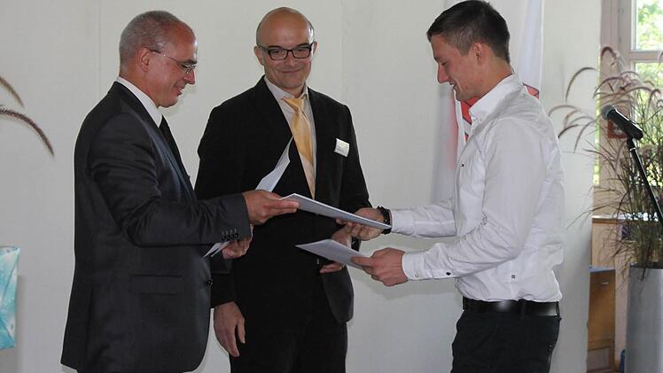 Absolvent Sandro Sommer (rechts) bekommt von Schulleiter Dr. Oliver Dünisch (links) und Kursleiter Stefan Andritschke (Mitte) sein Zeugnis überreicht.