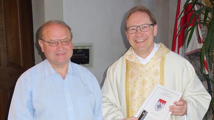 Pfarrer Thomas Eschenbacher (rechts) hat für Erich Schmitt eine Urkunde der Diözese Würzburg dabei. Foto: Jana Keul
