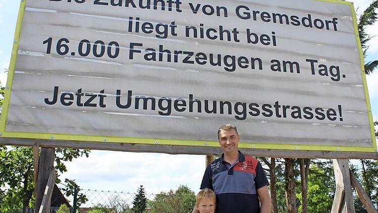 Bürgerinitiativensprecher Markus Franke mit Sohn Jakob vor einem der Banner, die die Initiative im Ort aufgehängt hat. Foto: Sabine Memmel