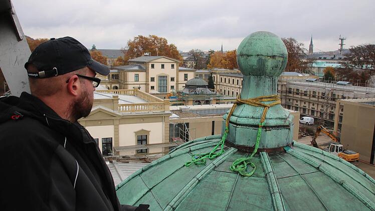 Mit dem Kran setzten Mitarbeiter der Firma Wiedamann die Kugel auf dem Dach des westlichen Eckpavillons wieder auf. Foto: Ralf Ruppert
