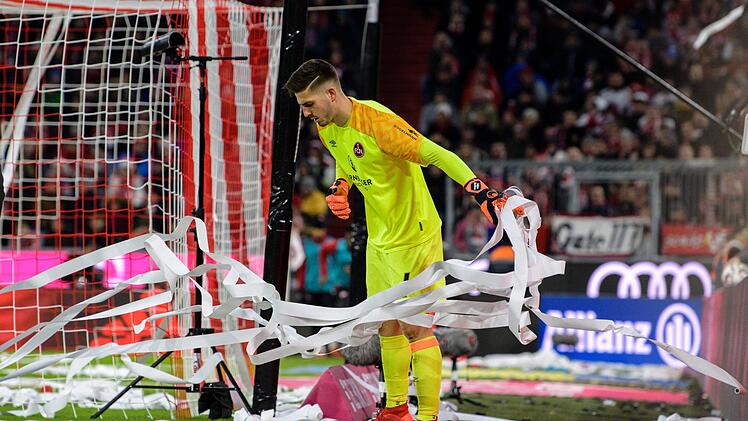 Torwart Fabian Bredlow von N&uuml;rnberg befreit sein Tor von den Papierstreifen, die von Fans zu Beginn der zweiten Halbzeit auf das Spielfeld geworfen wurden. Foto: Matthias Balk/dpa