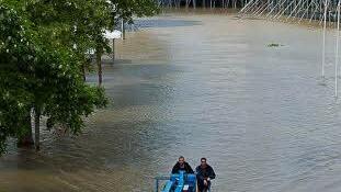 Helfer fahren am Sonntag mit einer Hebebühne in Würzburg durch die Überfluteten Wiesen auf dem Gelände des Africa-Festivals. Foto: Tobias Köpplinger