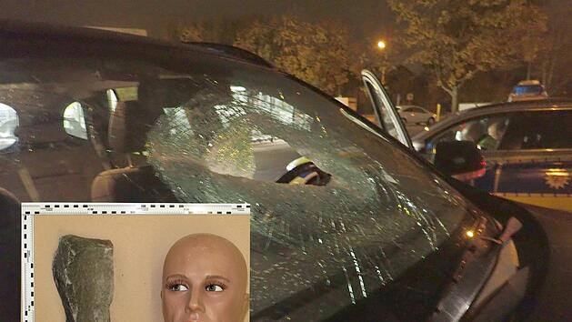 Die Bildkombo zeigt die durchschlagene Windschutzscheibe eines Autofahrers auf der A42. Das kleinere Bild zeigt, wie groß der Stein ist, der auf das Fahrzeug geworfen wurde. Fotos: Polizei