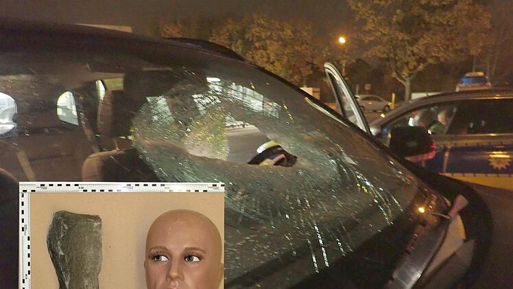Die Bildkombo zeigt die durchschlagene Windschutzscheibe eines Autofahrers auf der A42. Das kleinere Bild zeigt, wie groß der Stein ist, der auf das Fahrzeug geworfen wurde. Fotos: Polizei