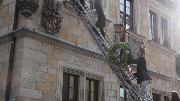 Unter dem Redner stehen die fünf Jahrgangsbesten. Sie reichen die Kränze und Gläser hinauf.