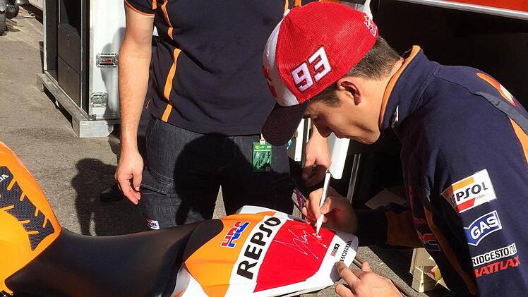Marc Marquez unterschreibt auf der Repsol-Honda von Thomas Beck (hinten)