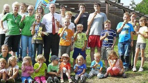 Gemeinsam schleckt es sich am besten. Genüsslich verputzten Kinder, Betreuer und Gäste das von Bürgermeister Franz Uome (hinten siebter von links) spendierte Eis. Mit im Bild die Jugendsprecher Irina Haber (hinten achte von links) und das Team des Spielmobiles (hinten links).  Foto: Klaus-Peter Wulf