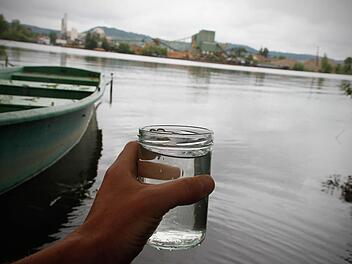 Ein Glas mit Wasser aus dem Sander Baggersee ist am 27.05.2014 in Sand am Main (Bayern) zu sehen. Bei 13 Badestellen bundesweit wurde die Wasserqualität als schlecht eingestuft, die EU-Mindestnormen wurden dort nicht erfüllt. Darunter waren der Sander See in der Nähe von Haßfurt. Foto: Rene Ruprecht/dpa