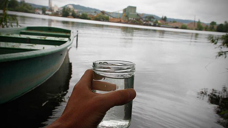 Ein Glas mit Wasser aus dem Sander Baggersee ist am 27.05.2014 in Sand am Main (Bayern) zu sehen. Bei 13 Badestellen bundesweit wurde die Wasserqualität als schlecht eingestuft, die EU-Mindestnormen wurden dort nicht erfüllt. Darunter waren der Sander See in der Nähe von Haßfurt. Foto: Rene Ruprecht/dpa