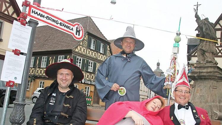 Gag zum 11.11. auf dem Staffelsteiner Marktplatz: Der Staffelsteiner Karnevals-Klub (SKK) eröffnet sein "Haam-Bring-Bänkla". Unter der Aufsicht von Erstem Präsidenten Matthias Graß haben hier (vorn v. l.) Jo Riemer, Margit Schnapp und Michael Hess Platz genommen. Foto: Matthias Einwag