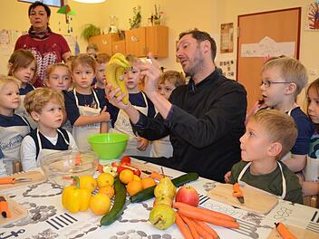 TV-Koch Mirko Reeh erklärt den Kindern, wie Obst und Gemüse zerkleinert werden. Foto: Gabi Bertram