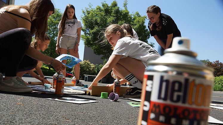 Mit Spraydosen gehen die Schülerinnen im Hof vor dem Schulgebäude ans Werk.Foto: Arkadius Guzy