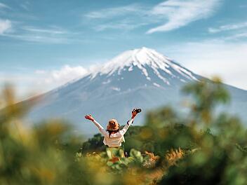Eine fr&ouml;hliche Touristin, die sich mit offenen Armen am Kawaguchiko-See mit dem Berg Fuji in Japan vergn&uuml;gt, Fr&uuml;hling und Sommer, Urlaub in Japan Happy tourist traveler woman enjoying with open arms on lake kawaguchiko with mount fuji in japan, spring and summer, Japan travel vacation