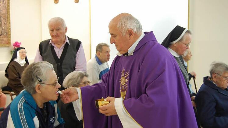 Gemeindepfarrer Josip Kos kommt bei der Eucharistiefeier zu jedem Gemeindemitglied und überreicht die Hostie.
