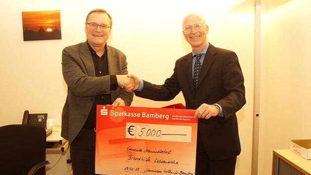 Bambergs Oberbürgermeister Andreas Starke (links) übergibt einen Scheck an den Memmelsdorfer Bürgermeister Gerd Schneider für die Brandopfer in Lichteneiche.  Foto: Joseph Beck