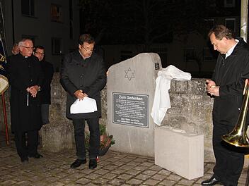 Pfarrer Volkmar Gregori, Bürgermeister Walter Ziegler und Pfarrer Mathias Rusin (von links) bei der Enthüllung des "Koffers" am Gedenkstein in Ebelsbach.  Günther Geiling