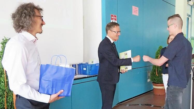 Statt Händeschütteln gab es für den Schulleiter Peter Gerhardt und den Absolventen Christoph Lehe eine Corona-Begrüßung; vorne links der Klassleiter der 10a, Andreas Herbst.