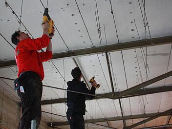 Zwei Handwerker bohren an der Decke des zukünftigen Friseursalons. Noch in diesem Jahr soll der Umbau fertig werden. Foto: Robert Huger