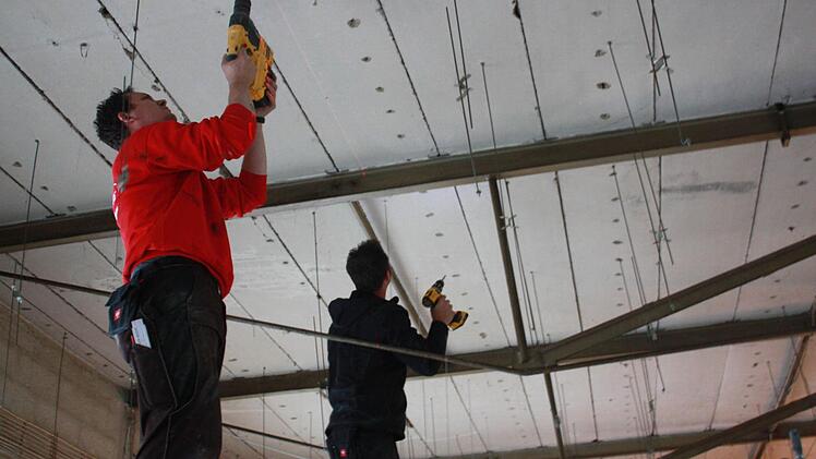 Zwei Handwerker bohren an der Decke des zukünftigen Friseursalons. Noch in diesem Jahr soll der Umbau fertig werden. Foto: Robert Huger