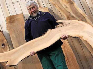 Hans-Karl Hertel mit einem kurios geformten Apfelbaum-Brett, das zum Beispiel mit LED-Leuchten bestückt zum Blickfang einer Wohnung werden kann. Seine eigene gute Stube in Horsdorf hat er mit vielen Holzornamenten stilvoll ausgestattet. Fotos: Matthias Einwag
