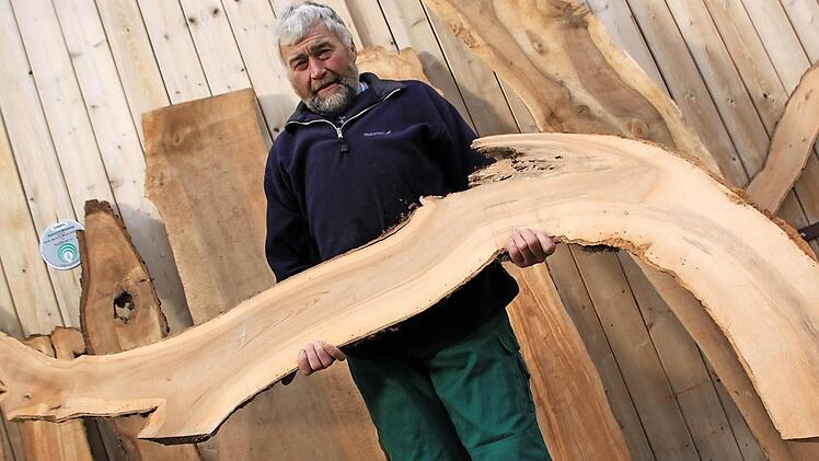 Hans-Karl Hertel mit einem kurios geformten Apfelbaum-Brett, das zum Beispiel mit LED-Leuchten bestückt zum Blickfang einer Wohnung werden kann. Seine eigene gute Stube in Horsdorf hat er mit vielen Holzornamenten stilvoll ausgestattet. Fotos: Matthias Einwag