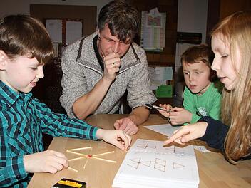 Konzentriert übt Kilian Stahl für die Mathematikmeisterschaft. Seine Geschwister Lena und Robin schauen ihm dabei zu. Den entscheidenden Hinweis gibt aber Papa Peter Stahl. Foto: Ulrike Müller