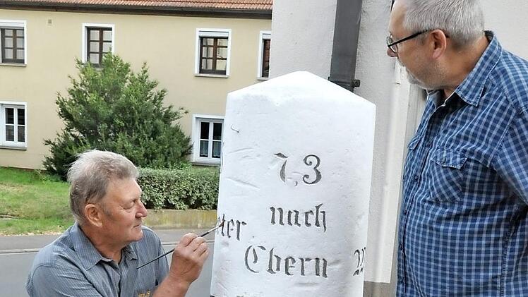 Malermeister Hilmar Martin hat vor allem den gemeißelten Schriftzug gesäubert und nachgezogen. Mit auf dem Bild der Vorsitzende des Heimatvereins Pfarrweisach, Hermann Weidner  Foto: alc
