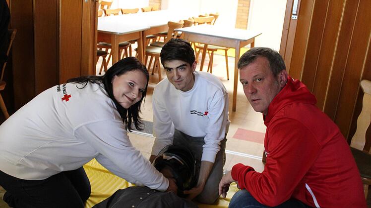Laura Lech und Dominik Schneider vom Roten Kreuz erkl&auml;ren Ralf Pratsch (Vorsitzender AMC Sonnefeld), wie man einen Helm von einer verletzten Person abnimmt. Das "Unfallopfer" ist Rallyeleiter Manfred Lenkheit. Foto: Cindy D&ouml;tschel