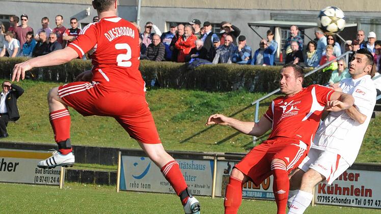 Die größere Dynamik bringt hier eindeutig Schondras Michael Müller ins Spiel. Das durch die Brückenauer Luft segelnde Spielgerät verfolgen FCler Adrian Neagu (rechts) und DJKler Tim Weiß, der das Derby mit seinem Tor entschieden hatte. Foto: Hopf
