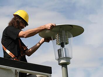 Ein Arbeiter wechselt einen Leuchtkopf einer Straßenlampe aus. Foto: Archiv/Jürger Gärtner