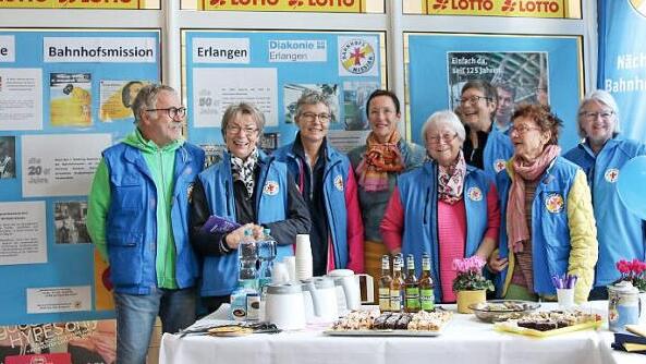Claudia Steubing, Leiterin der Bahnhofsmission Erlangen (3. v. l.) und Elisabeth Preuß, Zweite Bürgermeisterin der Stadt Erlangen (4. v.l .) mit Mitarbeitenden beim Tag der Bahnhofsmission am Erlanger Hauptbahnhof Foto: Diakonie Erlangen
