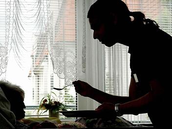 In einem Seniorenzentrum in Frankfurt (Oder) - hier eine Archivaufnahme aus dem Jahr 2004 -  füttert ein Pfleger eine Heimbewohnerin, die im Bett liegt.  Foto: Patrick Pleul/dpa/Archiv