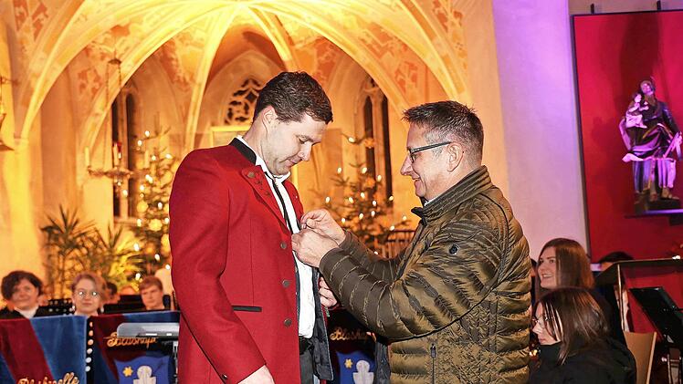 Michael Dinkel bekommt die Ehrennadel in Gold für 30 Jahre aktives Musizieren vom Kreisvorsitzenden des Nordbayerischen Musikbundes angesteckt.