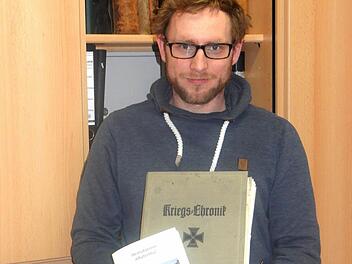 Pfarrer Michael Maul mit der alten "Kriegschronik" und der neuen Schrift, die der Heimatverein finanziert hat. Foto: Reinhard Löwisch