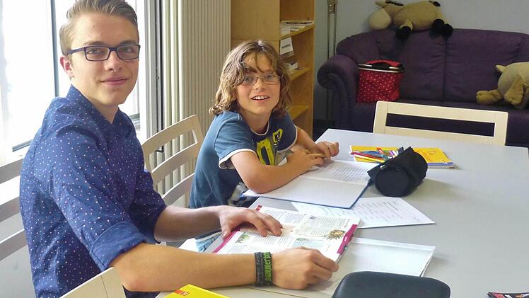 Der "Bufdi" Sebastian Spiegel hilft seinem Patenkind Florian Solihi bei den Hausaufgaben.