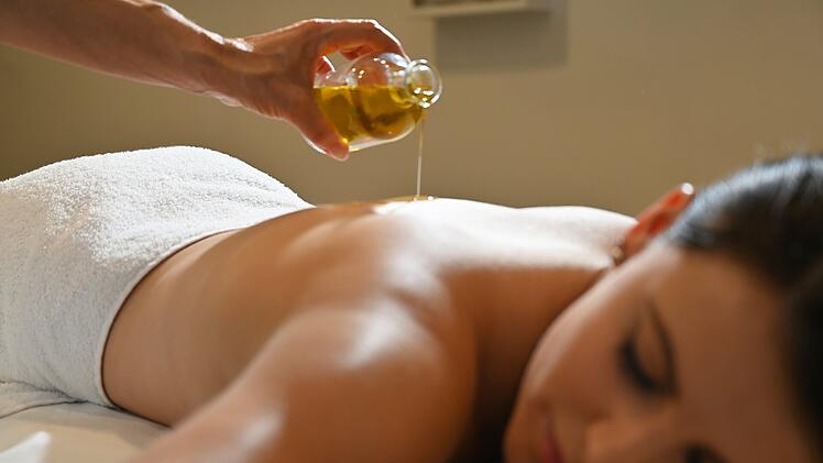 Eine Frau wird mit Massage-&Ouml;l begossen.