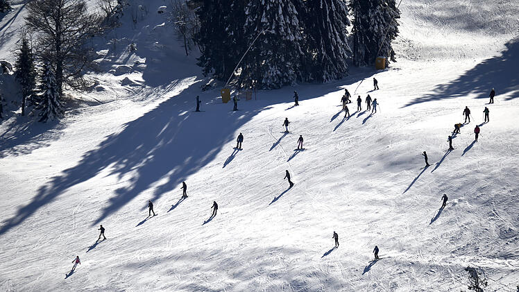 Aerial view of winter sportsmen with ski and snowboard. White snow slope on the mountain. People skiing and snowboarding. Germany, Black forest, Feldberg, Grafenmatt.