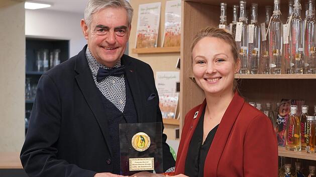 Matthias Weller ist einer der Hauptorganisatoren des 1. Rh&ouml;ner Schinken- und Destillationsmarkt in Rasdorf. Er &uuml;berreicht im Biosph&auml;renzentrum Rh&ouml;n Haus der Schwarzen Berge die Auszeichnung an die Brenner-K&ouml;nigin Franziska Bischof aus Wartmannsroth. Foto: Kathrin Kupka-Hahn
