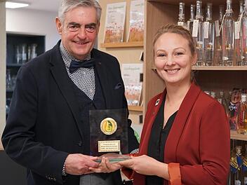 Matthias Weller ist einer der Hauptorganisatoren des 1. Rhöner Schinken- und Destillationsmarkt in Rasdorf. Er überreicht im Biosphärenzentrum Rhön Haus der Schwarzen Berge die Auszeichnung an die Brenner-Königin Franziska Bischof aus Wartmannsroth. Foto: Kathrin Kupka-Hahn