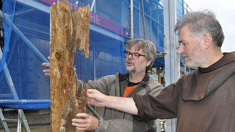 Architekt Georg Schilling und Pater Rufus begutachten einen morschen Holzbalken, der aus der Turmhaube stammt. Foto: Ingrid Kohles
