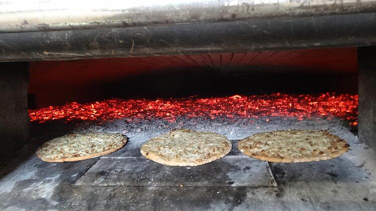 Tüchtig angeheitzt wurde der Holzbackofen. Der Ploatz liegt zum aufwärmen vor der Glut. Foto: Eckert