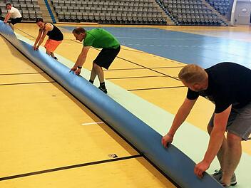 Alle packen für das Abenteuer Bundesliga mit an: Fleißige Helfer verlegen den Hallenboden mit handballspezifischen Linien, der nach den Statuten der Bundesliga Pflicht ist.  Foto: HSC