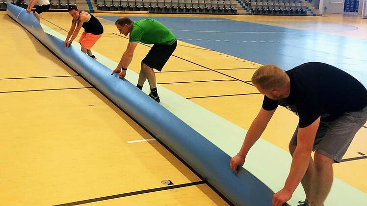 Alle packen für das Abenteuer Bundesliga mit an: Fleißige Helfer verlegen den Hallenboden mit handballspezifischen Linien, der nach den Statuten der Bundesliga Pflicht ist.  Foto: HSC