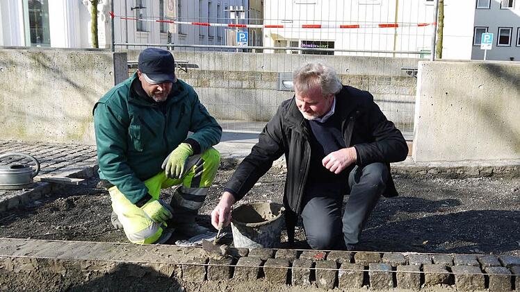 Beim Verfugen der Randsteine überlässt Arbeiter Sergej Akutin (links) ausnahmsweise dem Chef, Bernhard Ledermann, die Kelle. Foto: Ulrike Nauer