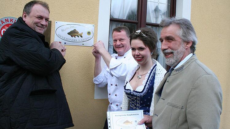 Landtagsabgeordneter Walter Nussel und Erich Weichlein (von links) befestigten das Schild im Eingangsbereich des Weingartsgreuther Landgasthofs. Rechts Walter Jakob und die Karpfenkönigin Katrin I.  Foto: Evi Seeger