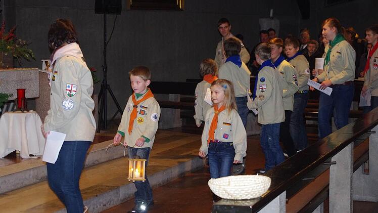Voller Stolz trägt Wölfling Jonas Baumann die Laterne mit dem Friedenslicht aus Bethlehem in die Friesener Kirche. Neben ihm ist die kleine Maria zu sehen.
