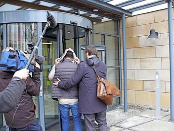 Der Verteidiger begleitet seinen Mandanten, der sein Gesicht hinter einer Zeitung versteckt, ins Erlanger Amtsgericht.  Foto: Karina Brock