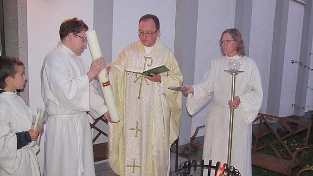 Die Christen in Creidlitz scharten sich zu Beginn der Osternachtfeier vor dem Osterfeuer an der St.-Elisabeth-Kirche. Daran entz&uuml;ndete  Kaplan Florian Sassik die neue Osterkerze. Foto: Martin Koch